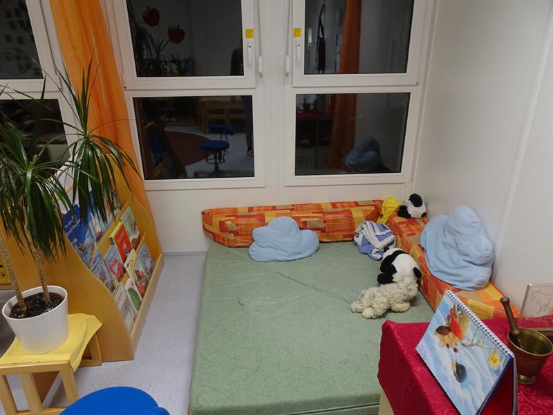 ein Zimmer mit grünem Teppich und einem Fenster mit einem Kuscheltier